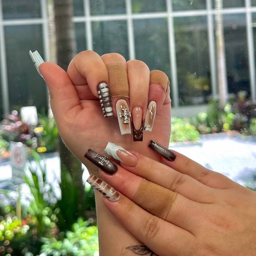 Recent NailMuseMiami nail set with brown and white marble nail art and cross charms